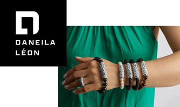 Brand visual for Daneila Léon featuring a model wearing handcrafted silver bracelets in pearl, gemstone, and leather styles — paired with a signature ring and green dress.