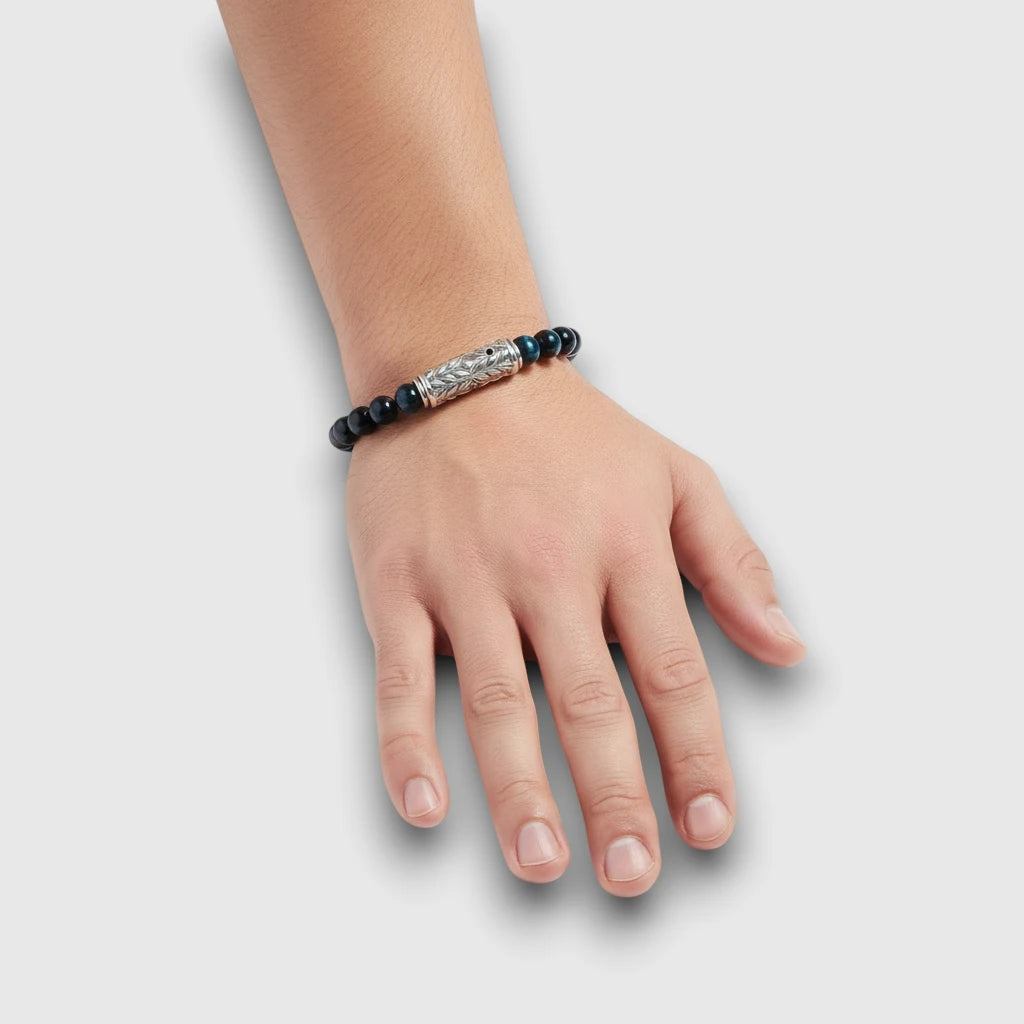 Sterling silver engraved clasp bracelet with dark blue tiger eye beads, shown worn on the wrist to demonstrate natural scale and fit.