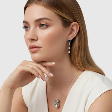 Model wearing long sterling-silver drop earrings with a blue sapphire and a matching sterling-silver pendant necklace with a pearl accent.