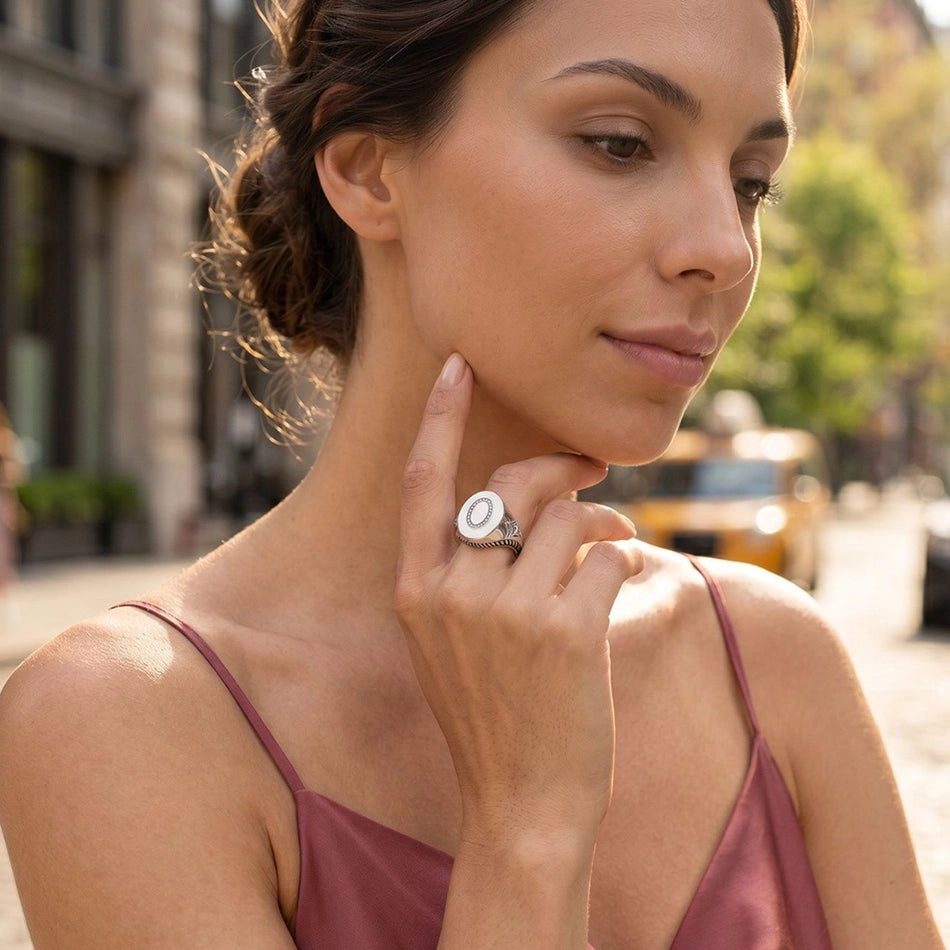 Woman wearing sterling silver signet ring with ivory enamel and diamond accents in luxury editorial street-style portrait