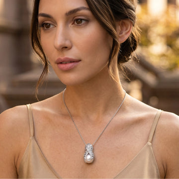Woman wearing a sterling silver pendant necklace with pearl and diamond accents in warm natural light editorial portrait outdoors.