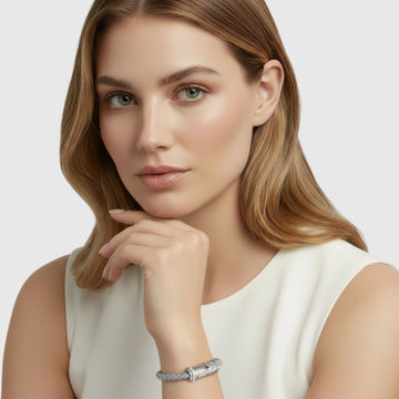 Unisex sterling silver and braided leather bracelet worn on the wrist, shown on a model in a minimal studio portrait.