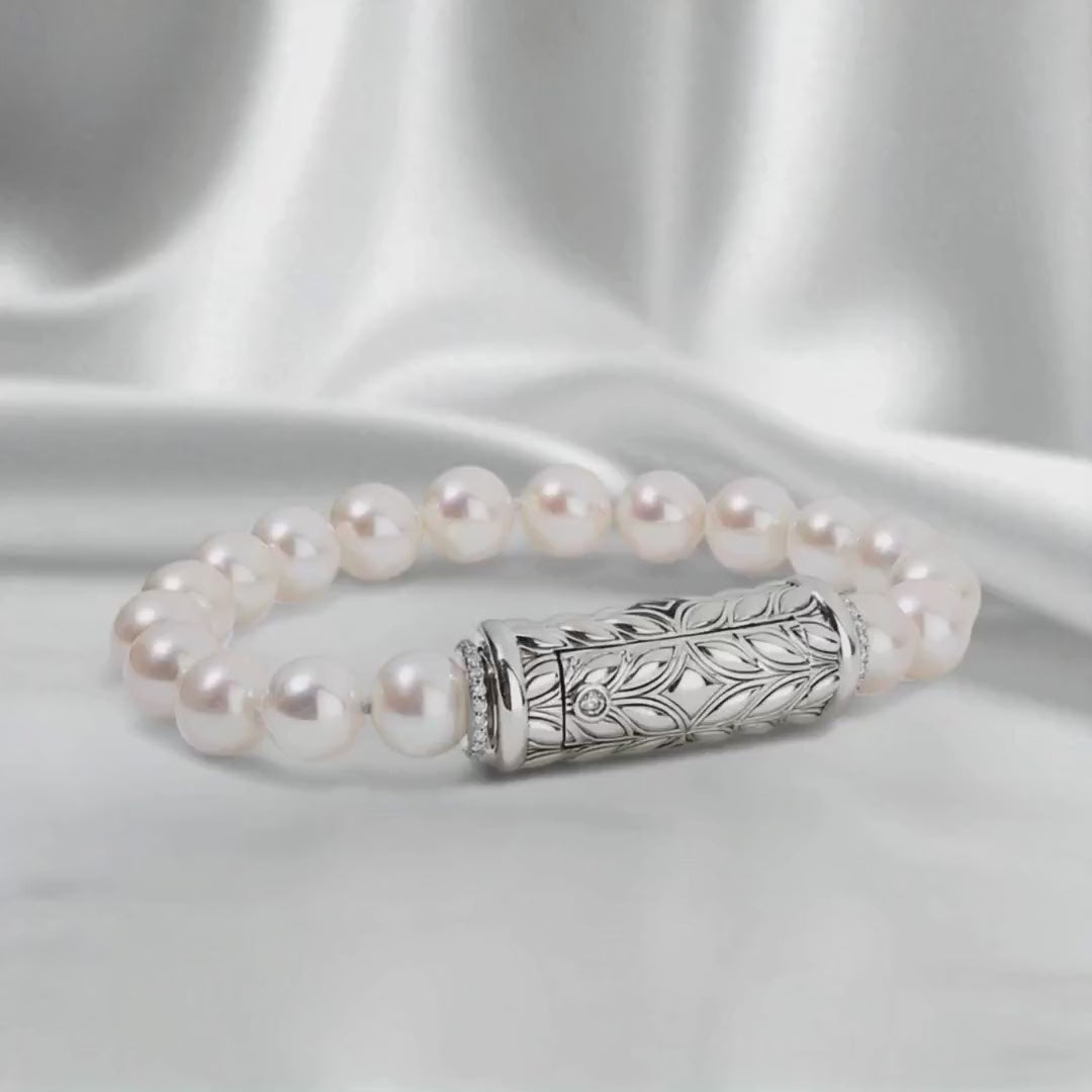 Silver bracelet with luminous white pearls and an engraved Persian Shield clasp, shown on white satin fabric in a slow side-to-side loop with soft diffused lighting highlighting the pearls’ natural luster and silver details.
