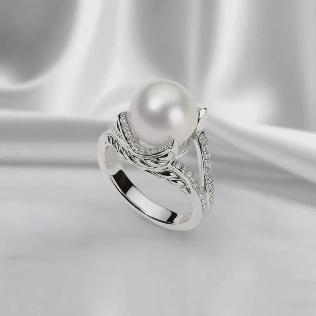 Silver ring with a round white pearl center stone and pavé lab-grown diamond accents, shown on white satin fabric in a slow side-to-side loop. Soft diffused lighting highlights the pearl’s natural luster and the handcrafted silver design.